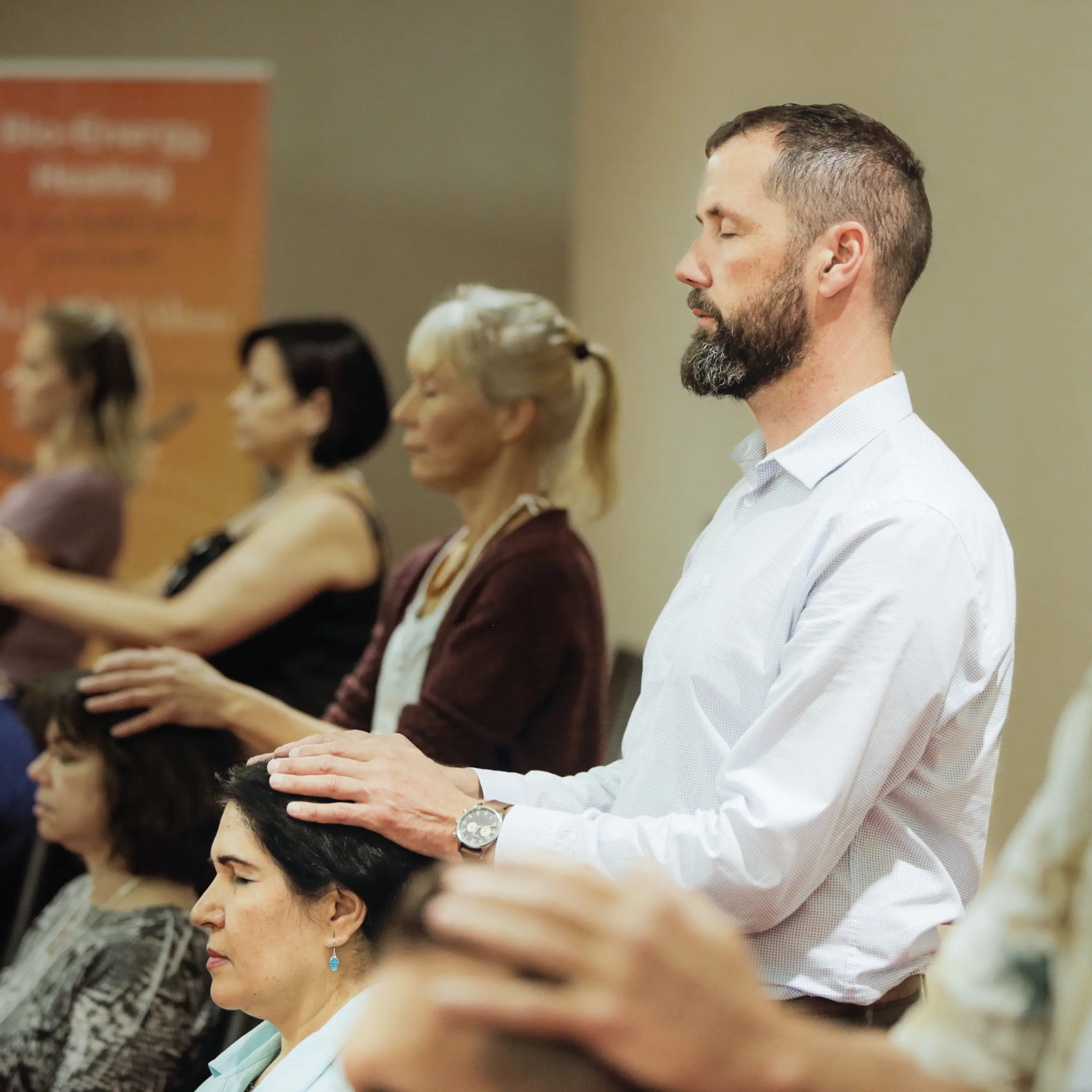 Michael D'Alton resting his hands on a seated student's head during a Bio-Energy Healing session